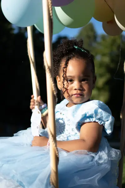 Retrato infantil con vestido azul en un columpio